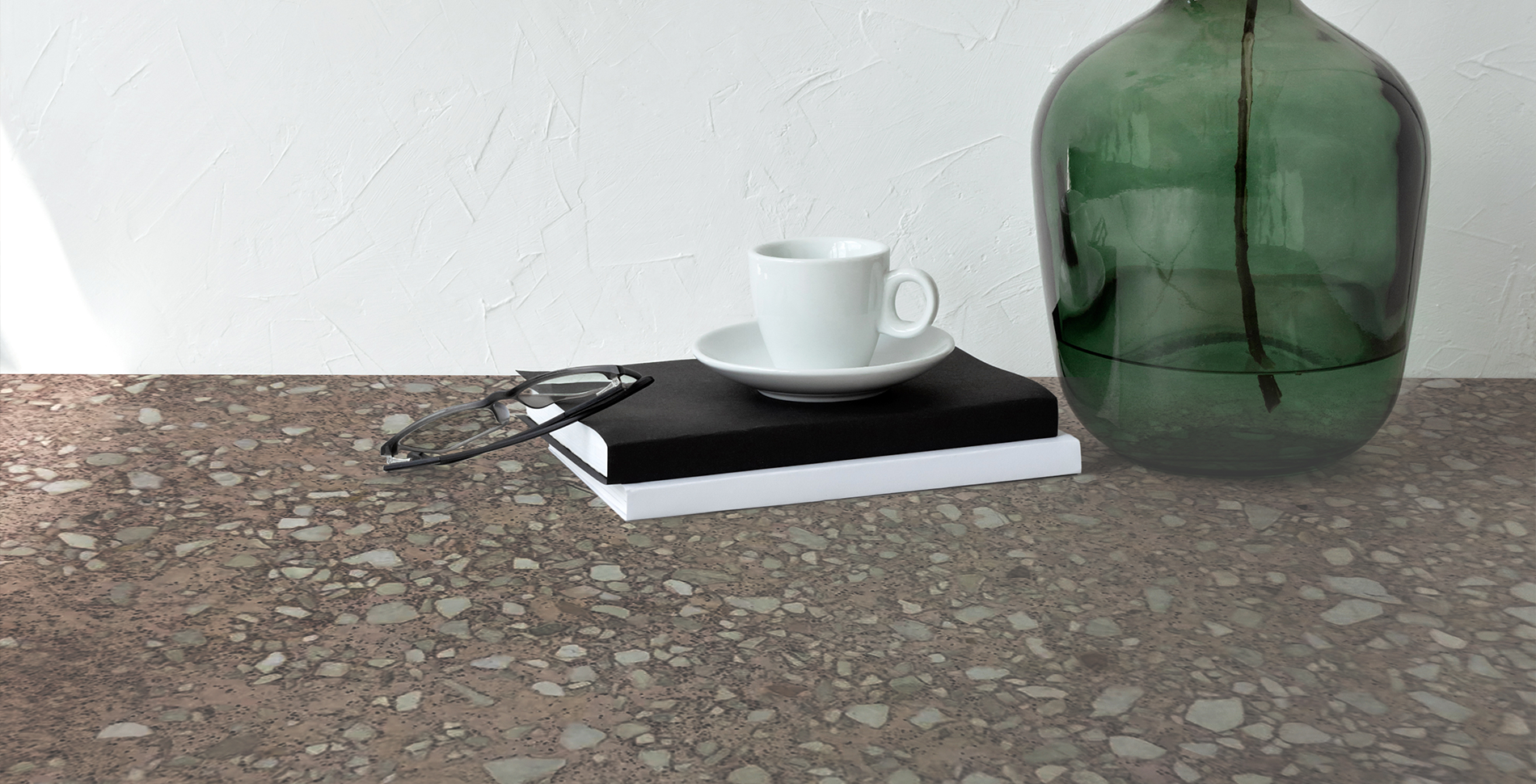 MONOLITH -  NEUTRO GRANA MEDIA NEW 20kg surface with a cup, notebook, and green vase, showcasing modern design and durability.